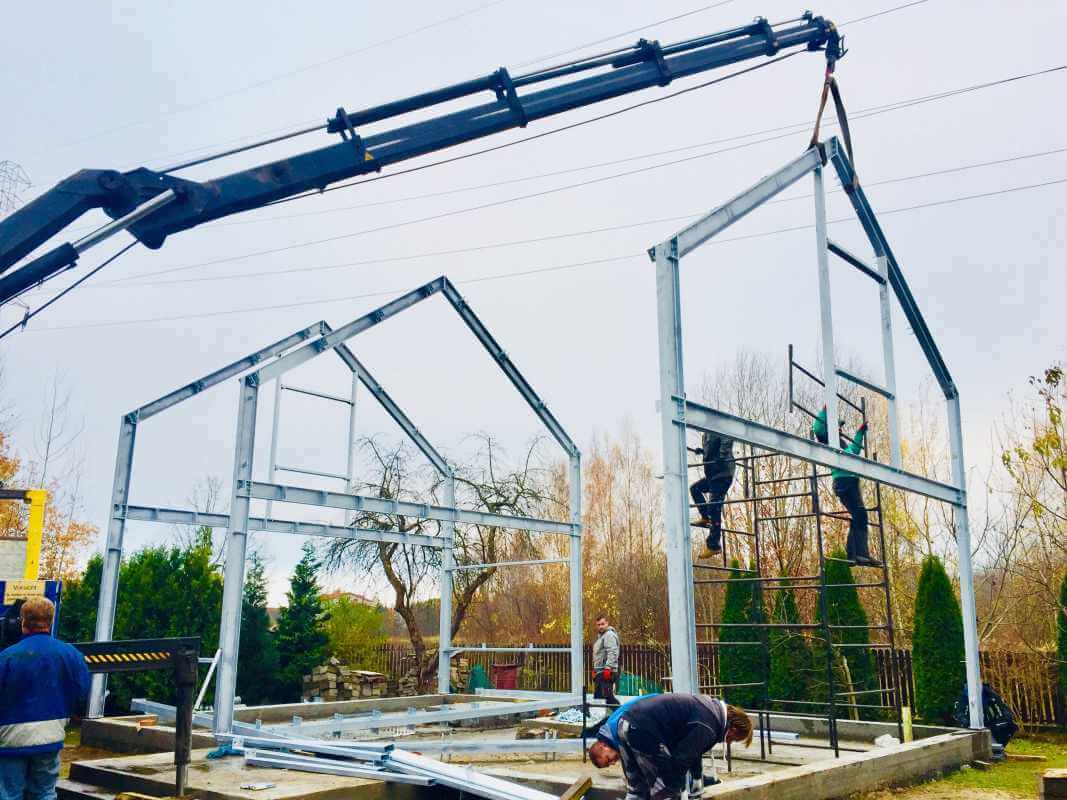Pracownicy montują konstrukcję stalową w trakcie budowy, w tym przypadku dokonano wybór projektu domu stalowego.