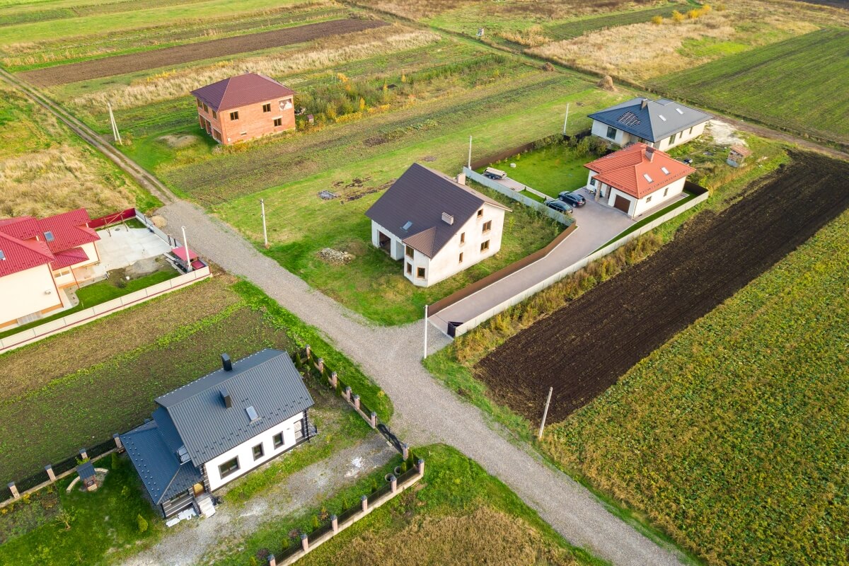 Obraz lotniczy przedstawiający proces budowy energooszczędnego domu stalowego na tle wiejskiego krajobrazu.